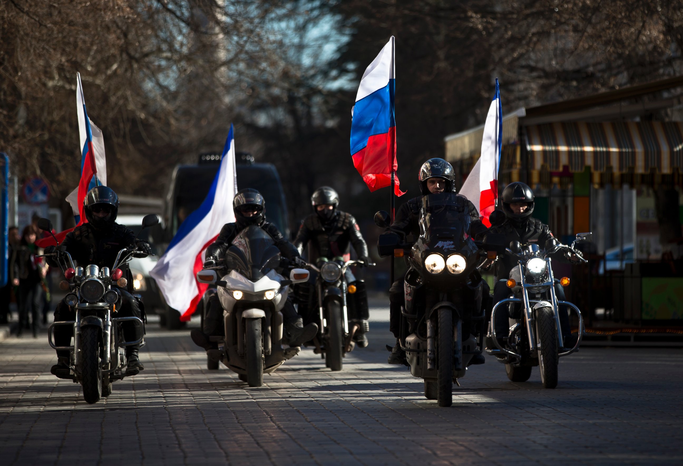 PHOTO: People on motorcycles decorated with Russian and Crimean flags drive in front of a van transporting the coffins  of Ukrainian soldiers during their funeral in Simferopol, Crimea, Saturday, March 22, 2014.