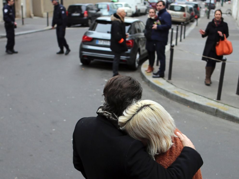 PHOTO: People stand outside the French satirical newspaper Charlie Hebdos office after a shooting, in Paris, Jan. 7, 2015.