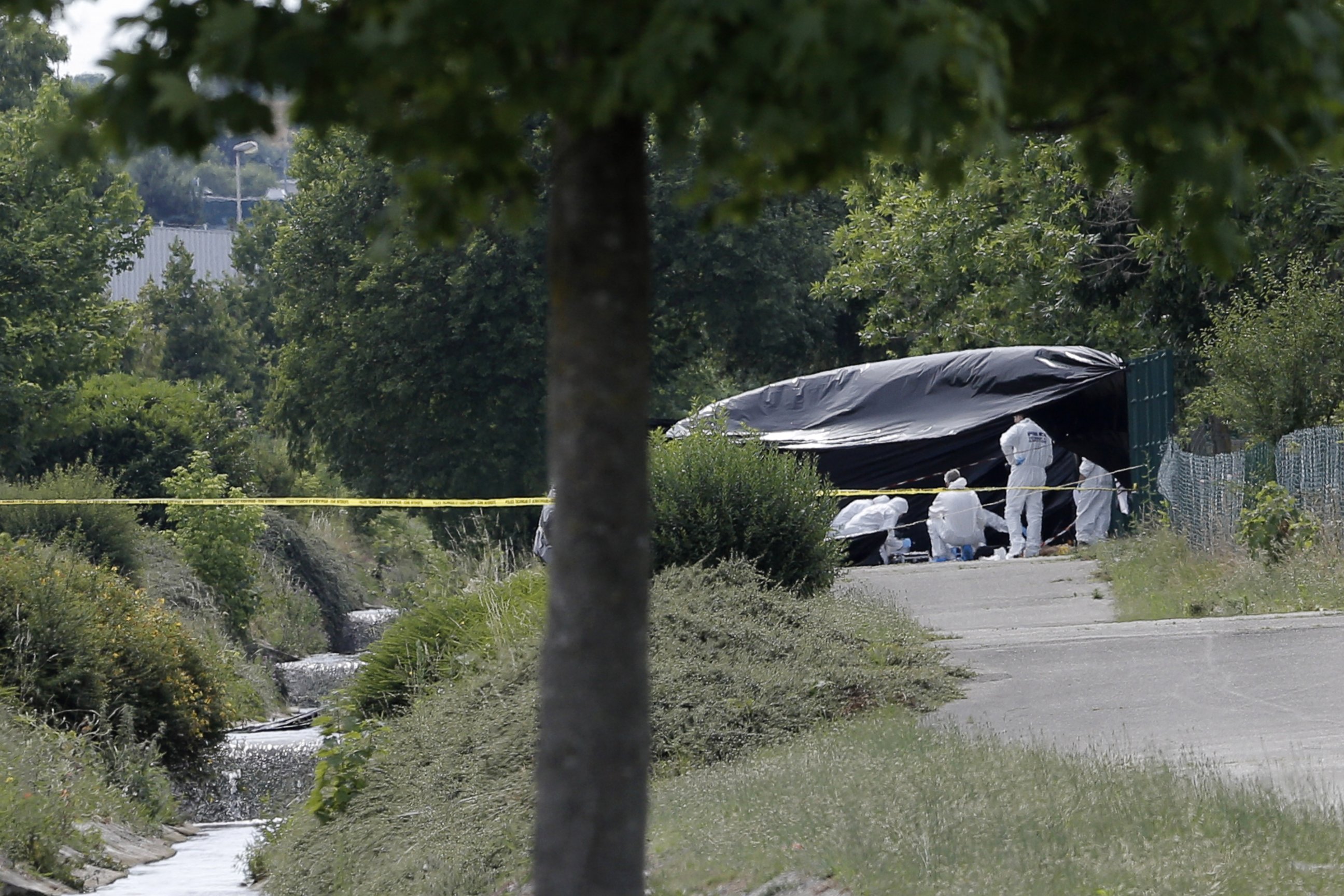 PHOTO: Police officers investigate next to the enclosed area near the Air Products company in Saint-Quentin-Fallavier, near Lyon, central eastern France, June 26, 2015.