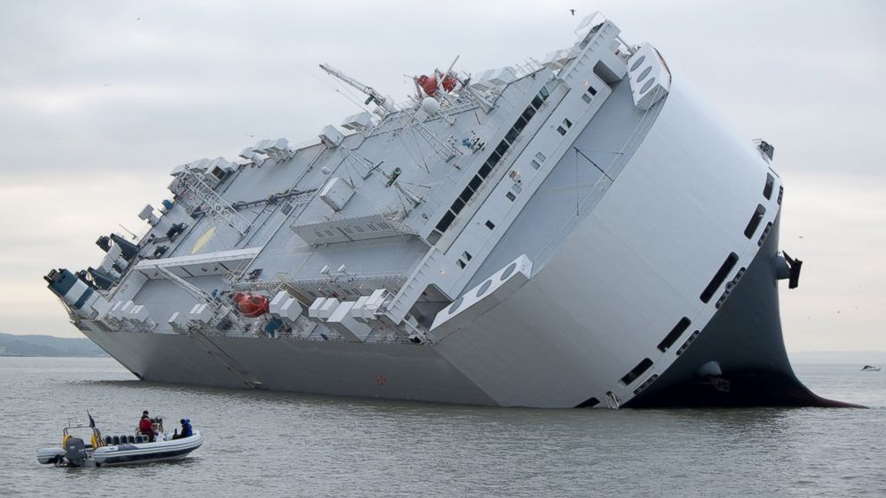 A small boat sails past the Hoegh Osaka car transporter cargo ship that ran aground in Solent, off the Isle of Wight, England, Jan. 4, 2015.