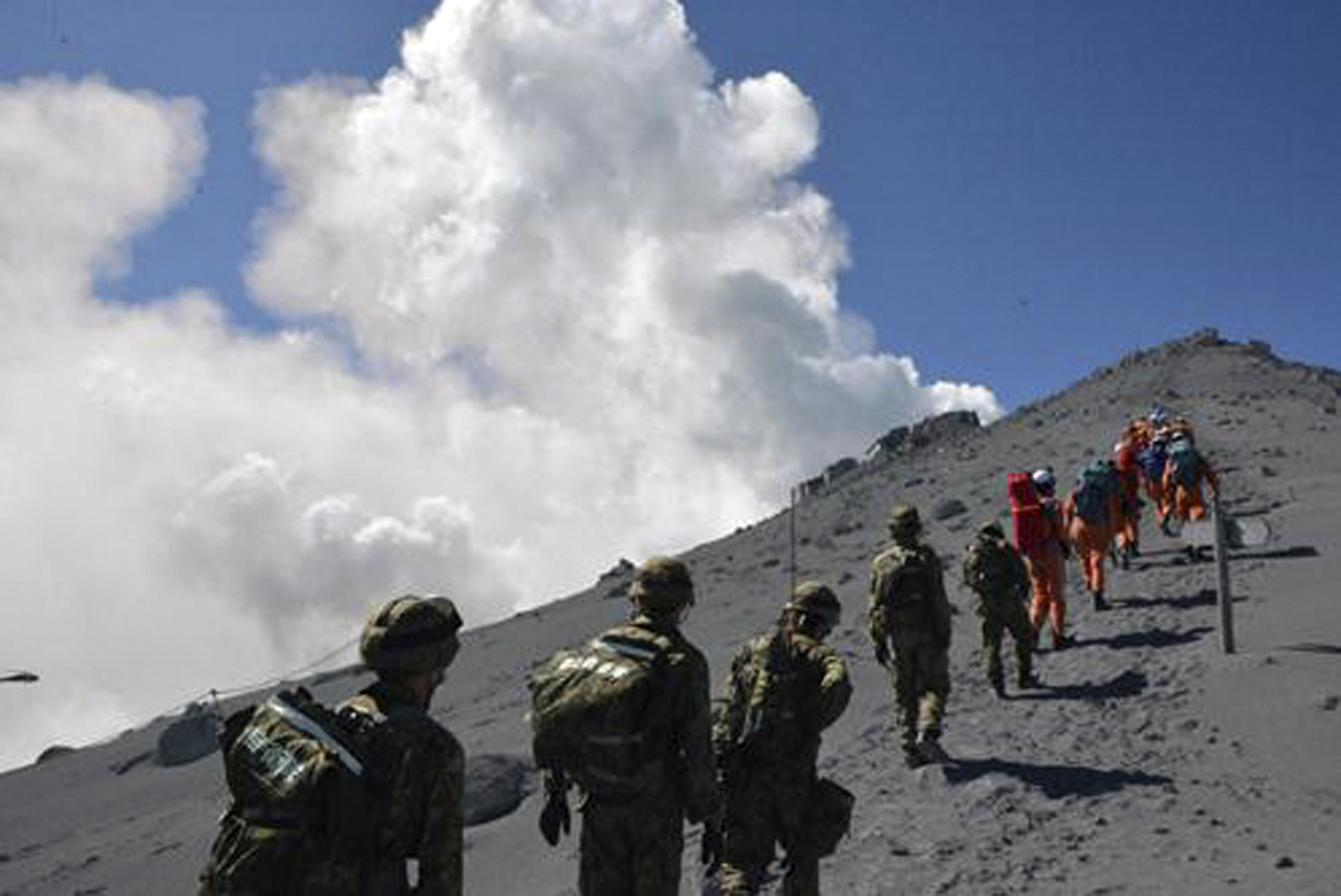 PHOTO: JGSDF personnel and fire fighters head for the summit of Mount Ontake to rescue people who have been trapped in the mountaintop lodge one day after the volcano became active in central Japan, Sept. 28, 2014.