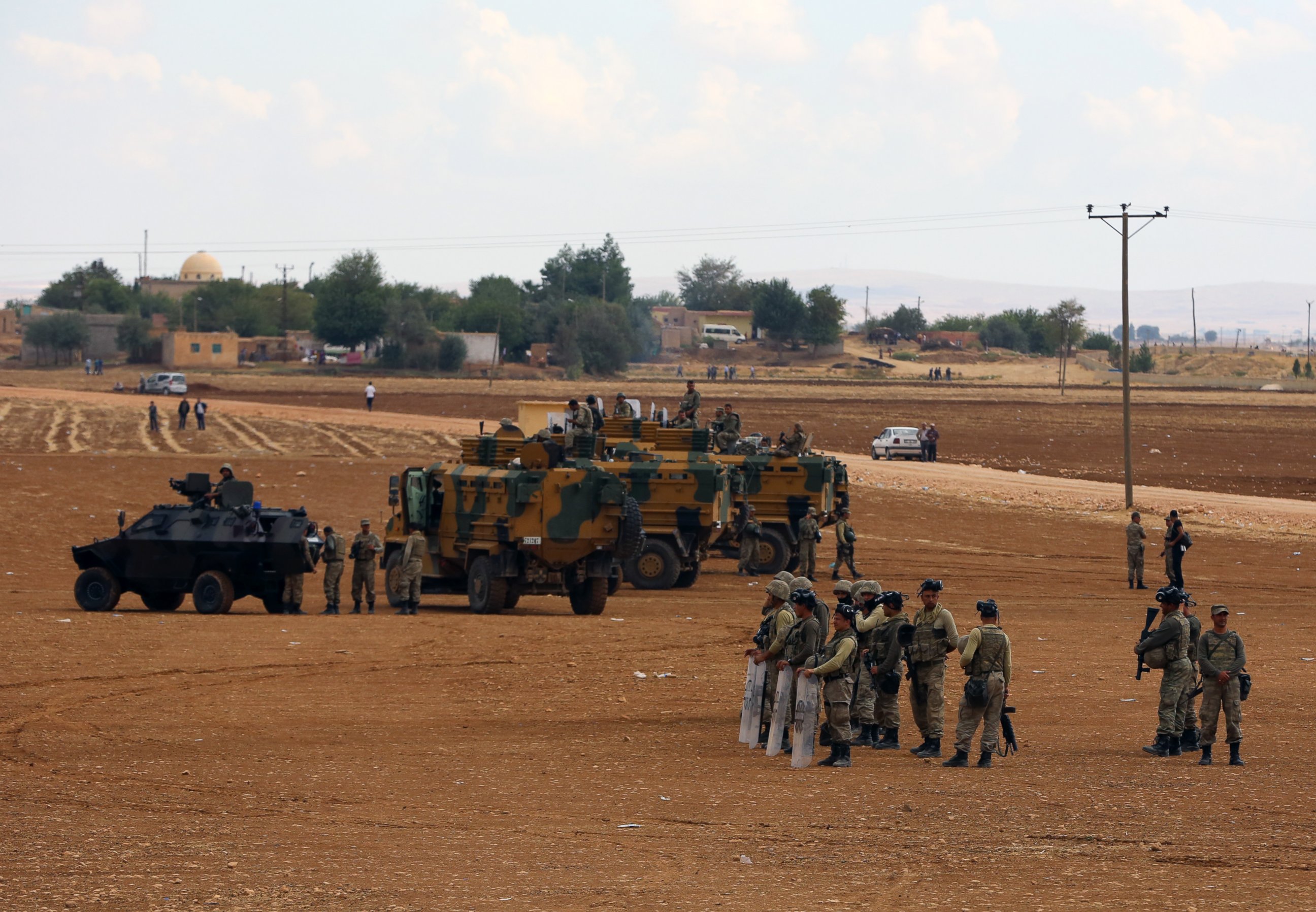 PHOTO: Turkish soldiers standby as Turkish Kurds gather nearby to express their solidarity with Kurdish fighters in Kobani, Syria, at the Turkey-Syria border near Suruc, Turkey, Sept. 29, 2014.