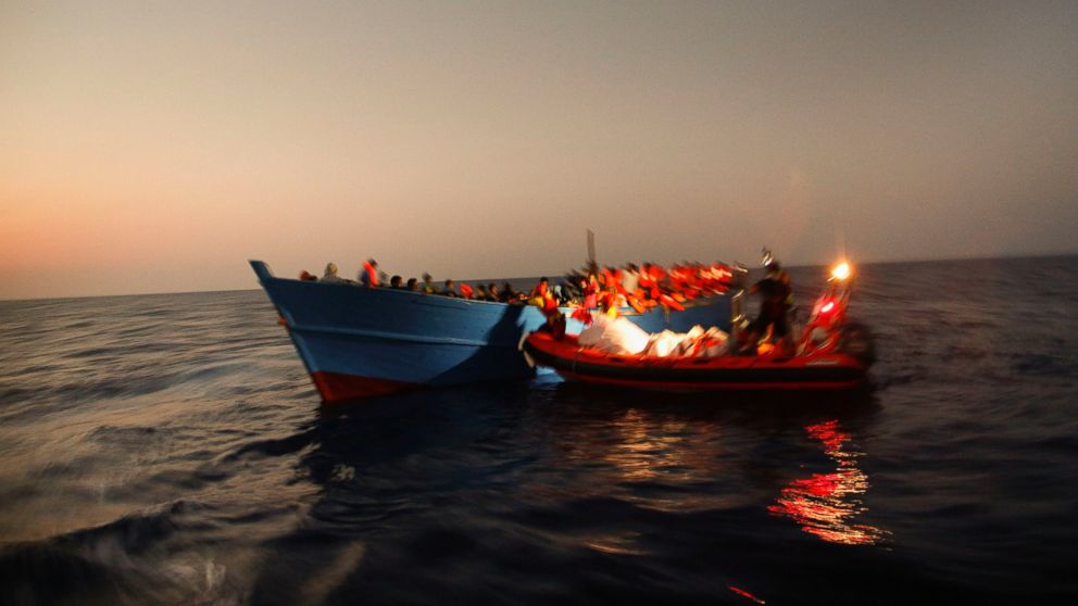 Migrants sailing in a crowded wooden boat carrying more than seven hundred migrants, are helped by members of an NGO during a rescue operation at the Mediterranean sea, about 13 miles north of Sabratha, Libya, Aug. 29, 2016.