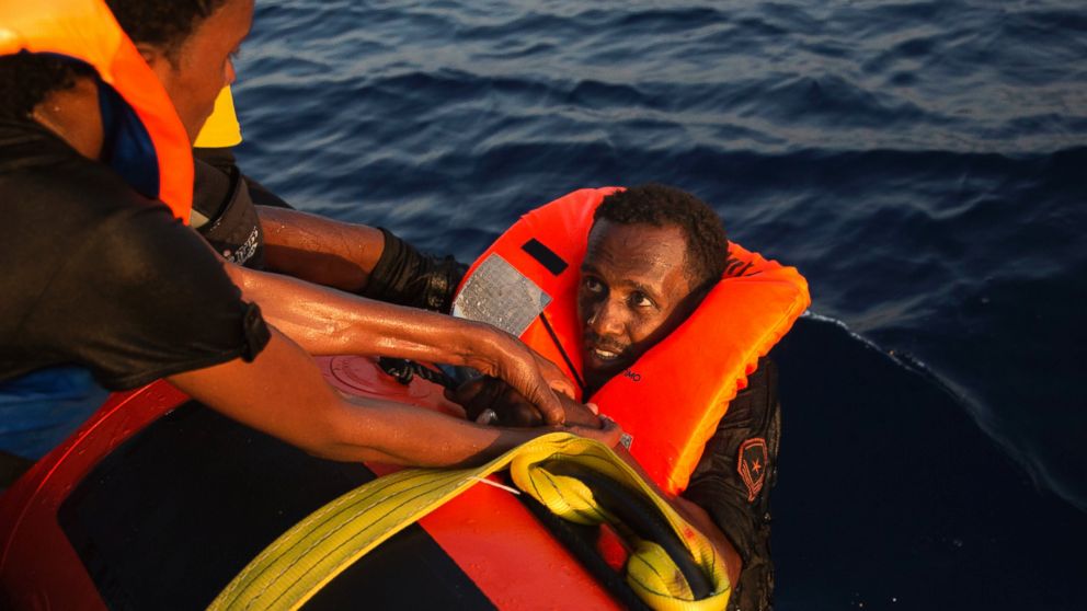 A migrant from Eritrea is helped after jumping into the water from a crowded wooden boat during a rescue operation in the Mediterranean sea, Aug. 29, 2016.