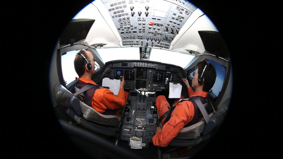 Captain of the Japan Coast Guard Gulfstream Makoto Hoshi, left, and his co-pilot Shunichi Yumiza sit in the cockpit during a search for the missing Malaysia Airlines Flight MH370 in the Southern Indian Ocean, near Australia, April 1, 2014. 
