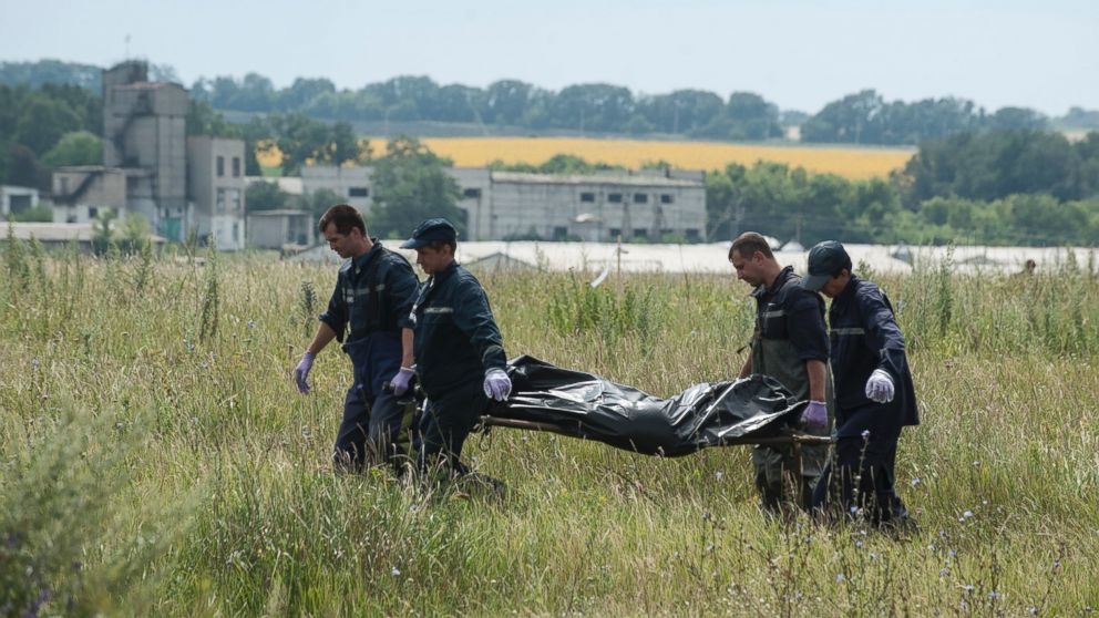 Rescue workers carry a plastic bag with a dead body at the crash site of a Malaysia Airlines jet near the village of Hrabove, eastern Ukraine, Saturday, July 19, 2014. 