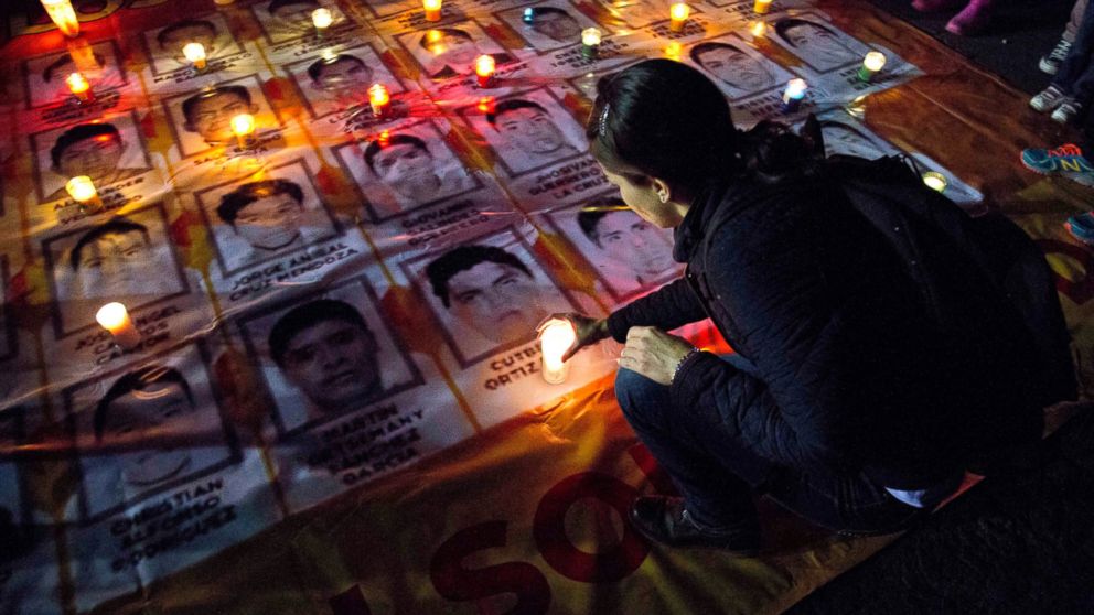 PHOTO: A woman places a candle on photos of the missing students during a protest against the disappearance of 43 students from the Isidro Burgos rural teachers college, in Mexico City, Oct. 22, 2014.