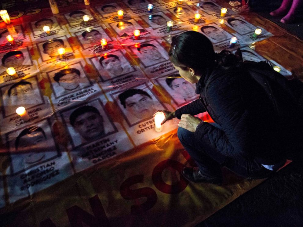 PHOTO: A woman places a candle on photos of the missing students during a protest against the disappearance of 43 students from the Isidro Burgos rural teachers college, in Mexico City, Oct. 22, 2014.