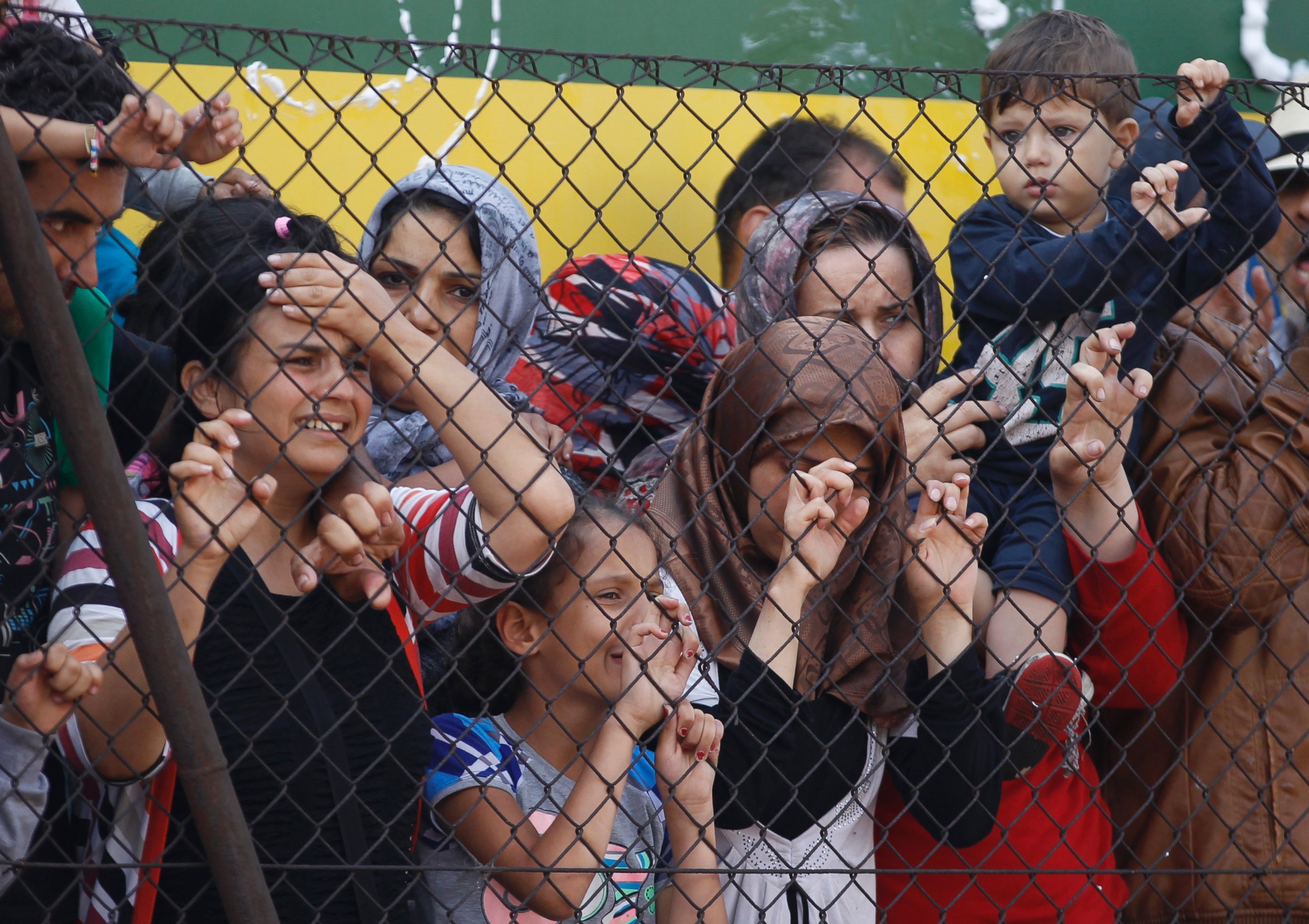PHOTO:People stand behind a fence net to a train that was stopped Thursday in Bicske, Hungary, Sept. 4, 2015. 