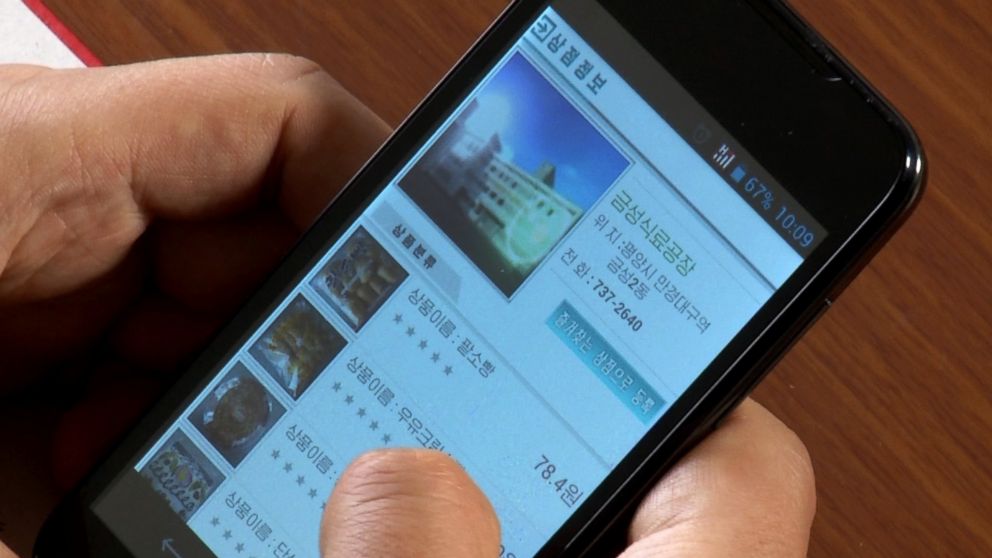 A man uses his smartphone to demonstrate how to use North Korea's new online shopping site, April 22, 2015.