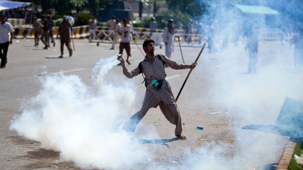 A Pakistani protester throws tear gas shell back towards police during a protest in Islamabad, Pakistan, Aug. 31, 2014. 