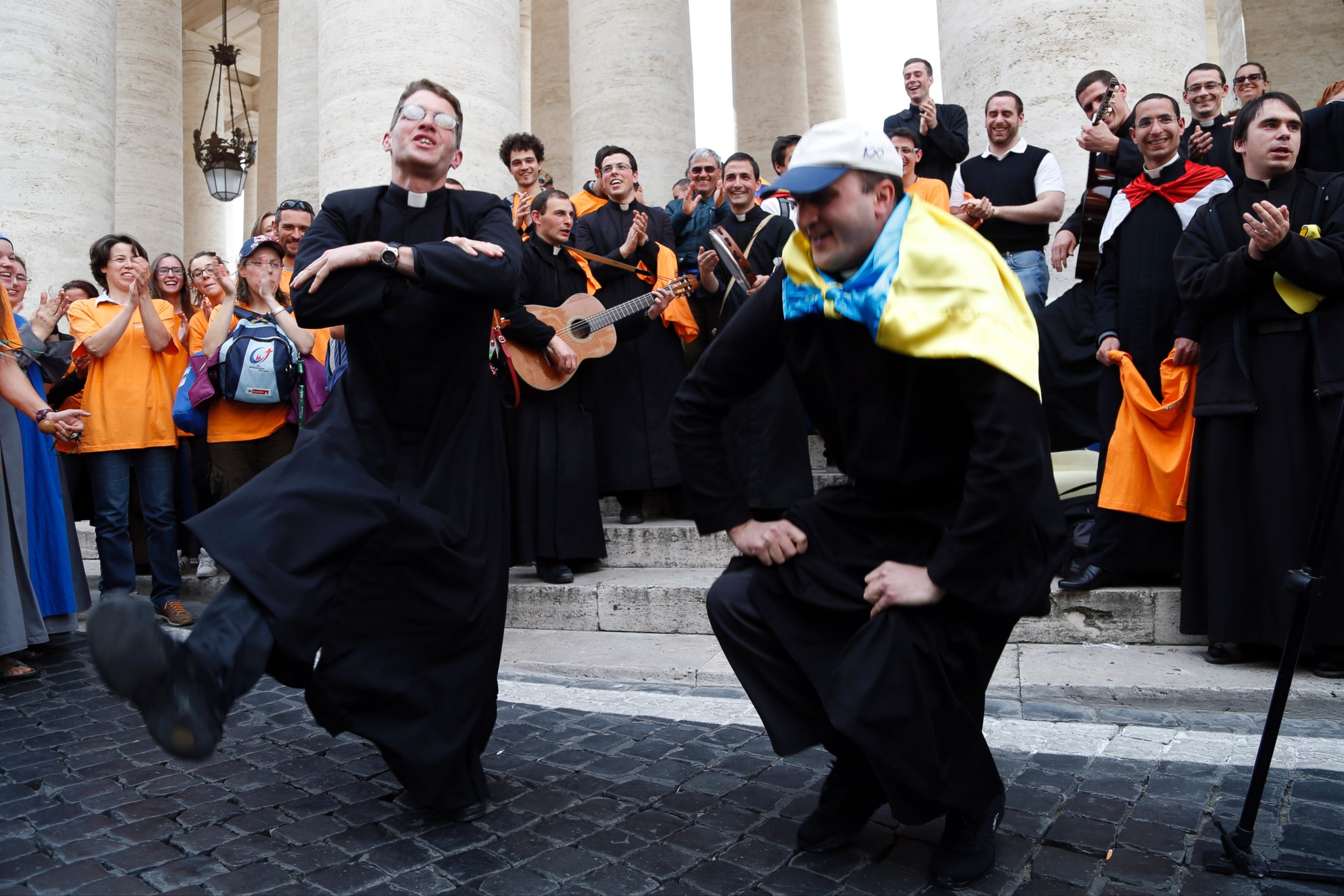 PHOTO: Two priests, one of them with an Ukrainian flag on his shoulders, dance in St. Peter's Square at the Vatican, Saturday, April 26, 2014.