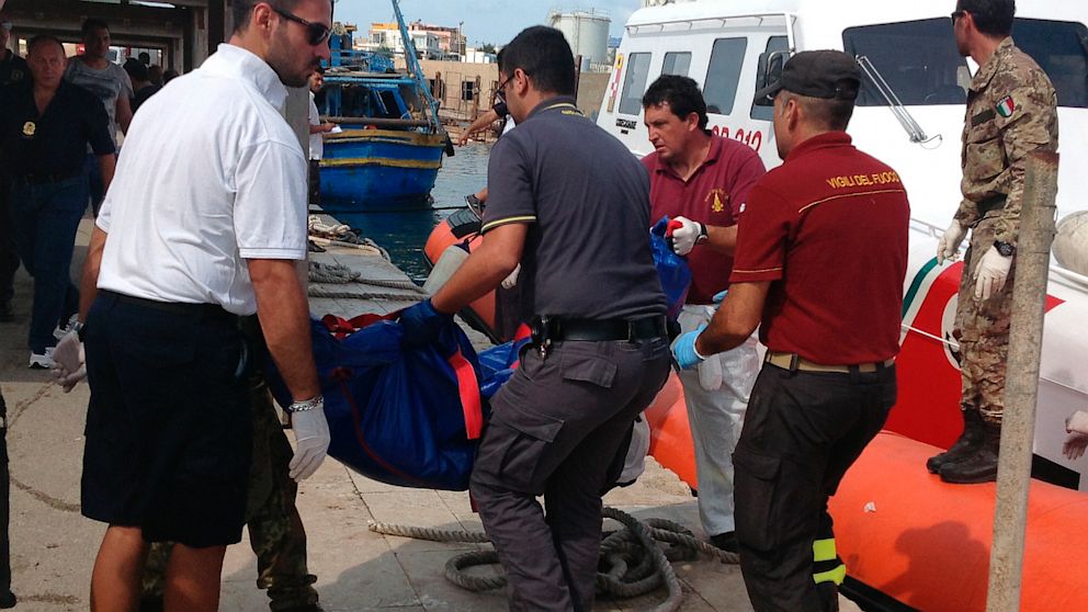 Firefighters unload the body of a drowned migrant from a Coast Guard boat in the port of Lampedusa, Sicily, Oct. 3, 2013. 