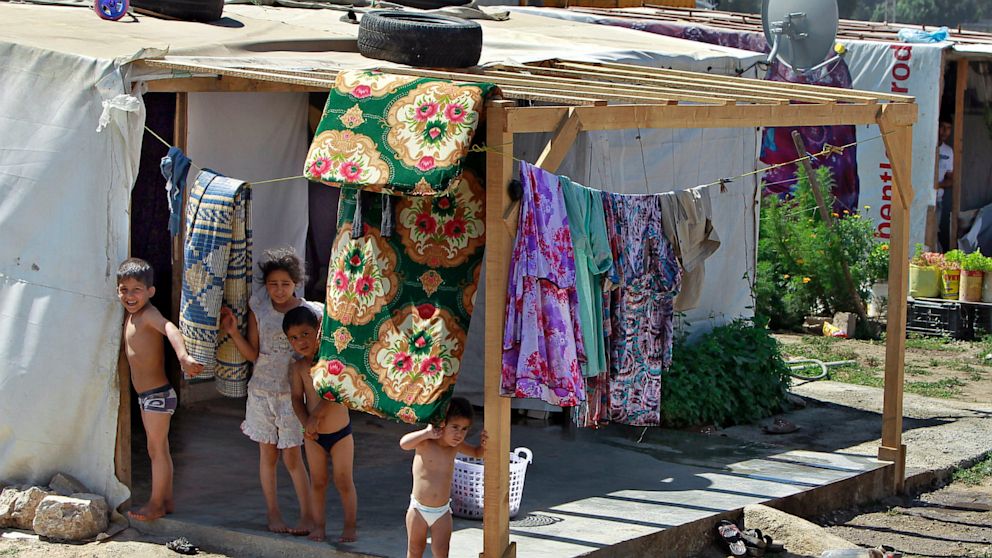 Syrian refugee children stand outside their tent at a temporary refugee camp in the eastern Lebanese town of Faour near the border with Syria, Lebanon, Aug. 28, 2013. 