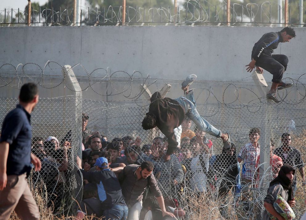 PHOTO: Syrian refugees cross into Turkey from Syria over and through a hole on the border fence in Akcakale, Sanliurfa province, southeastern Turkey, June 14, 2015.