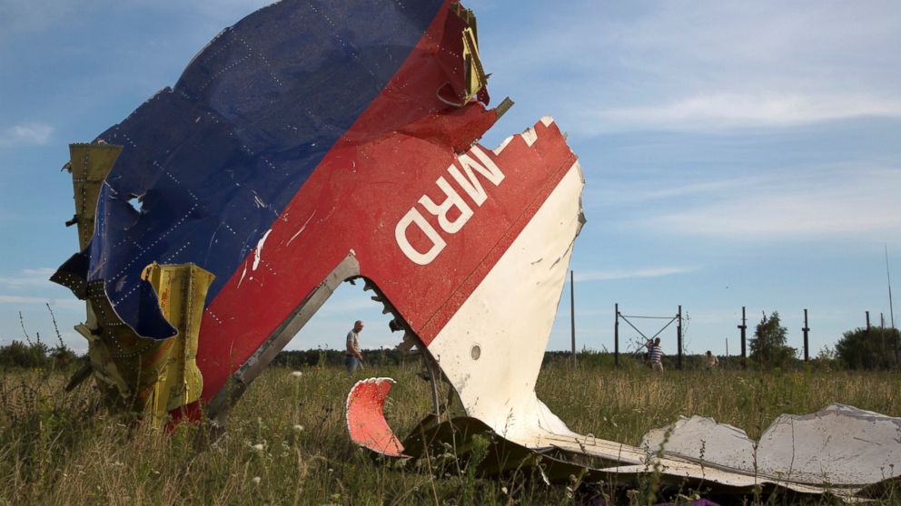 A man walks past a piece of the crashed Malaysia Airlines Flight 17 near the village of Hrabove, eastern Ukraine, July 21, 2014.