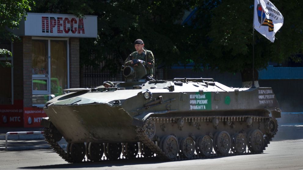 A pro-Russian militant sits atop an armored personal carrier with a Donetsk republic flag rolling through a street in Slovyansk, Ukraine, May 7, 2014.