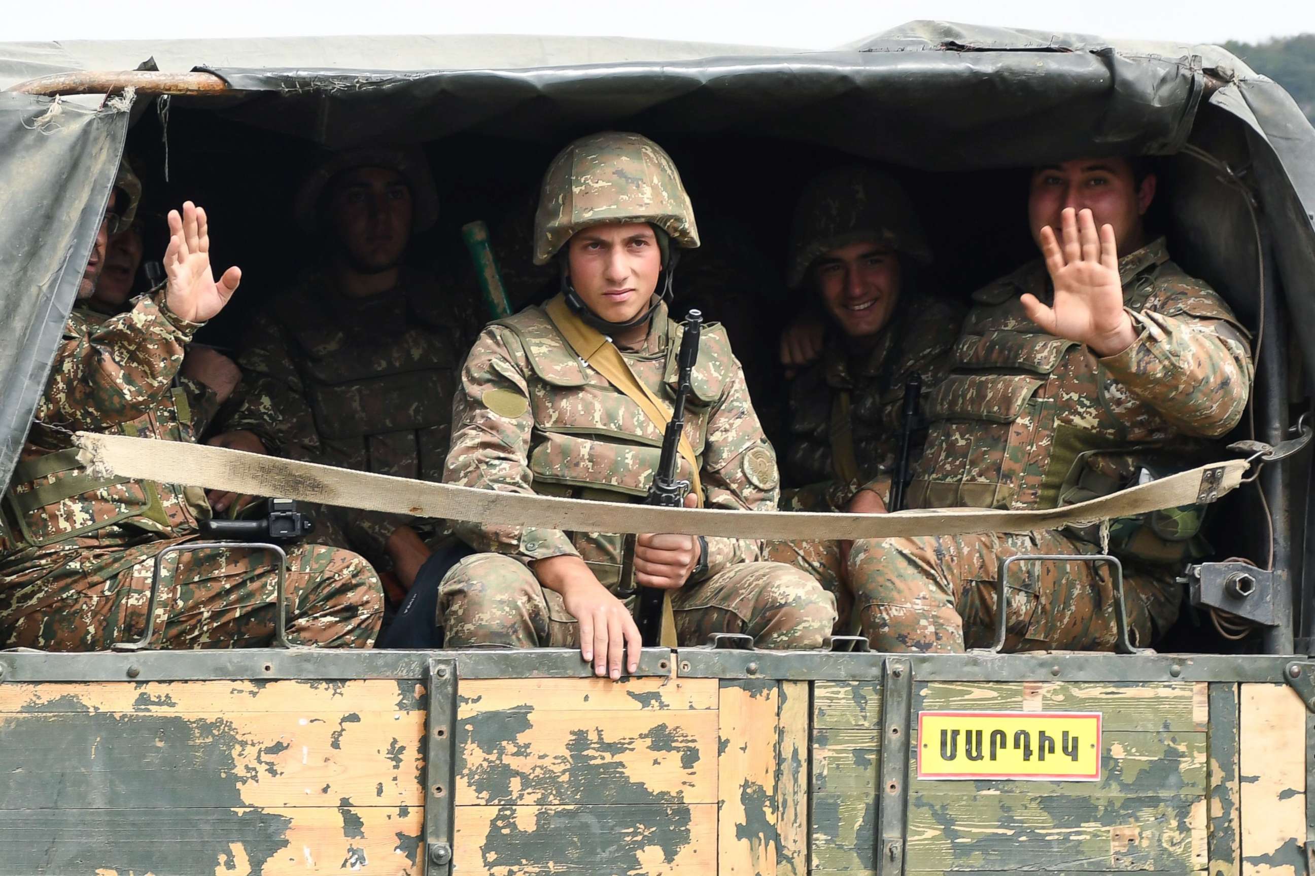 PHOTO: Servicemen of Karabakh's Defence Army wave while riding in the back of a truck on the way to the town of Martakert during fighting with Azerbaijan over the breakaway Nagorny Karabakh region, Sept. 29, 2020. 