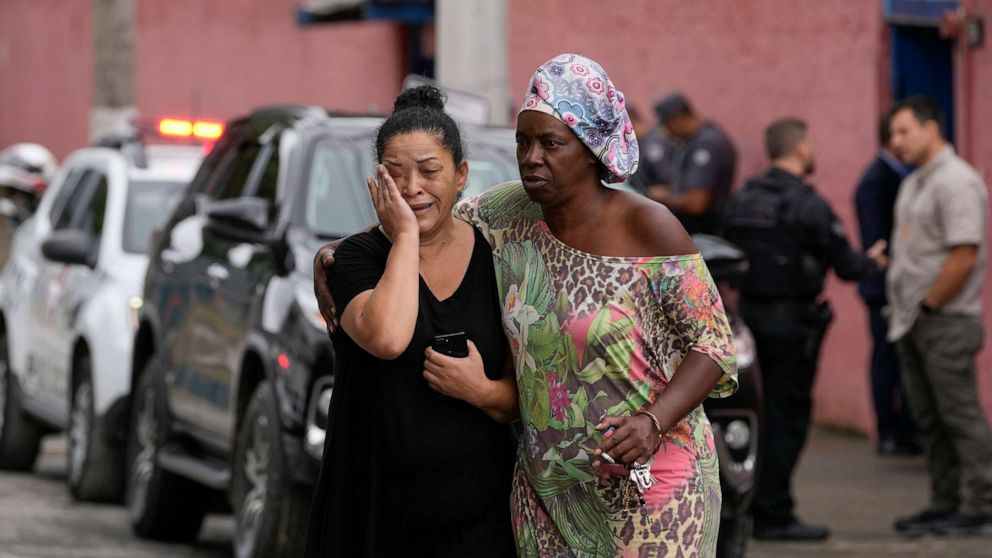 PHOTO: Silvia Palmieri, who is the mother of a teacher who survived a stabbing attack at the Thomazia Montoro school, left, leaves the school comforted by a friend in Sao Paulo, Brazil, March 27, 2023.