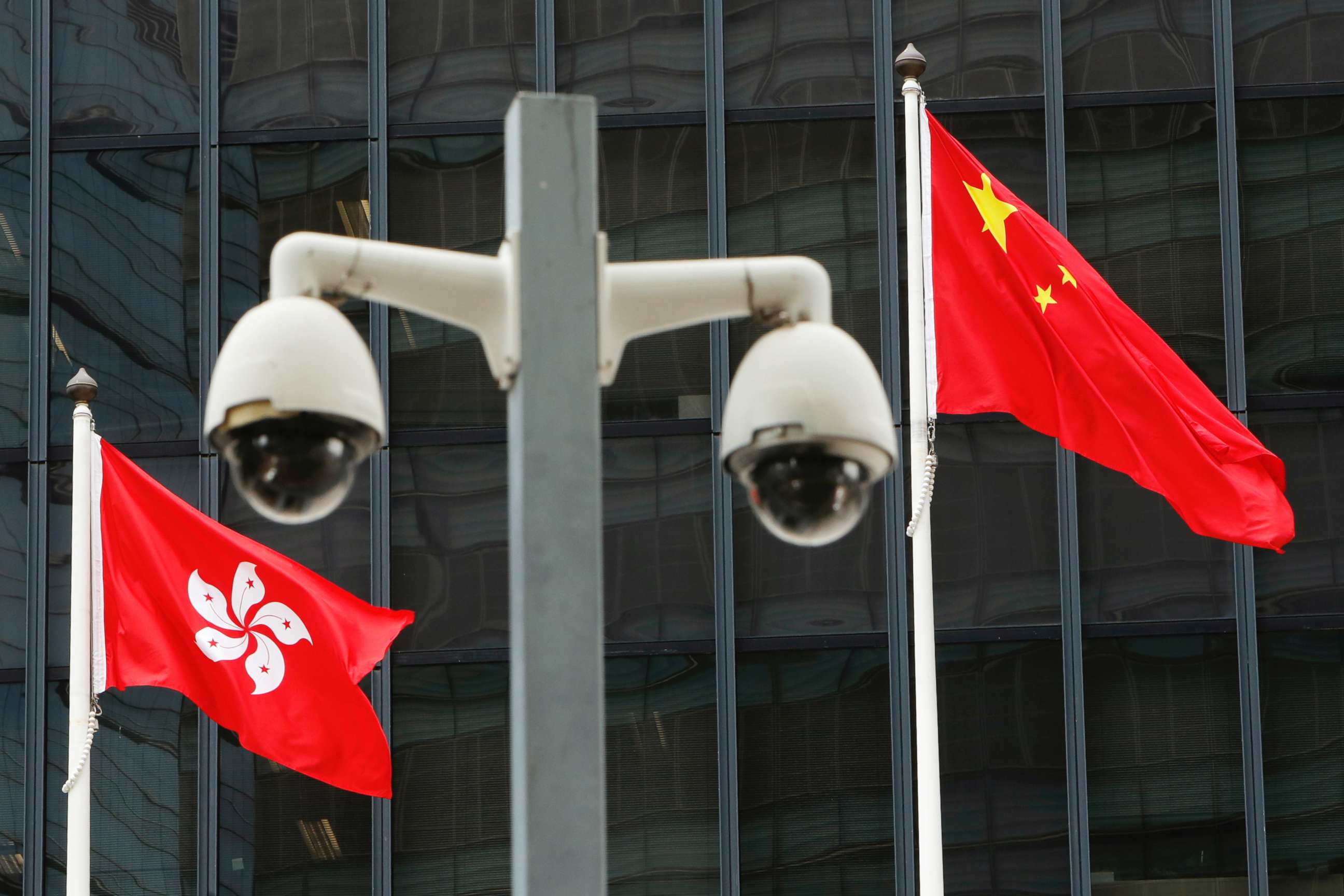 FILE PHOTO: Hong Kong and Chinese national flags are flown behind a pair of surveillance cameras outside the Central Government Offices in Hong Kong, China July 20, 2020.