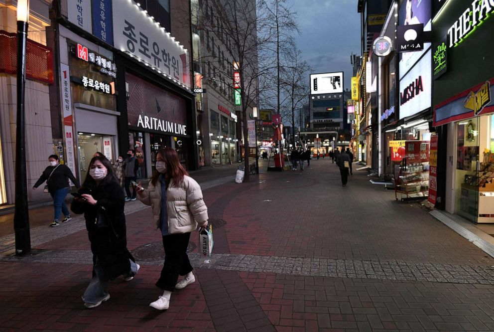 PHOTO: Pedestrians wearing face masks walk on the street at Dongseongro shopping district in the southeastern city of Daegu on February 24, 2020. 