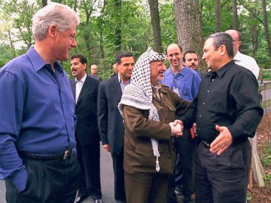 PHOTO: President Bill Clinton looks on while Palestinian leader Yasser Arafat and Israeli Prime Minister Ehud Barak shake hands on the opening day of the Mid-East peace talks July 11, 2000 at Camp David MD.
