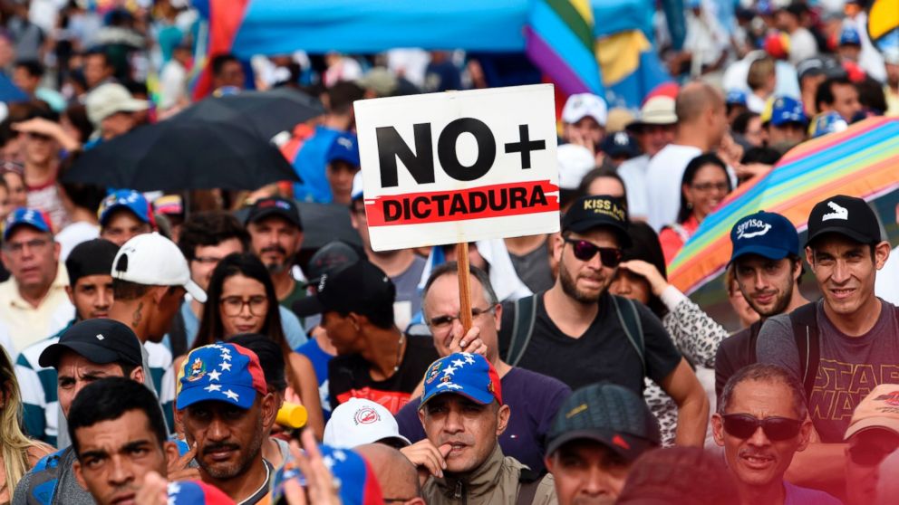 Venezuelan opposition activists, one holding a sign which translates to "No Dictatorship" take part in a rally against the government of President Nicolas Maduro, in Caracas, on May 18, 2017.
