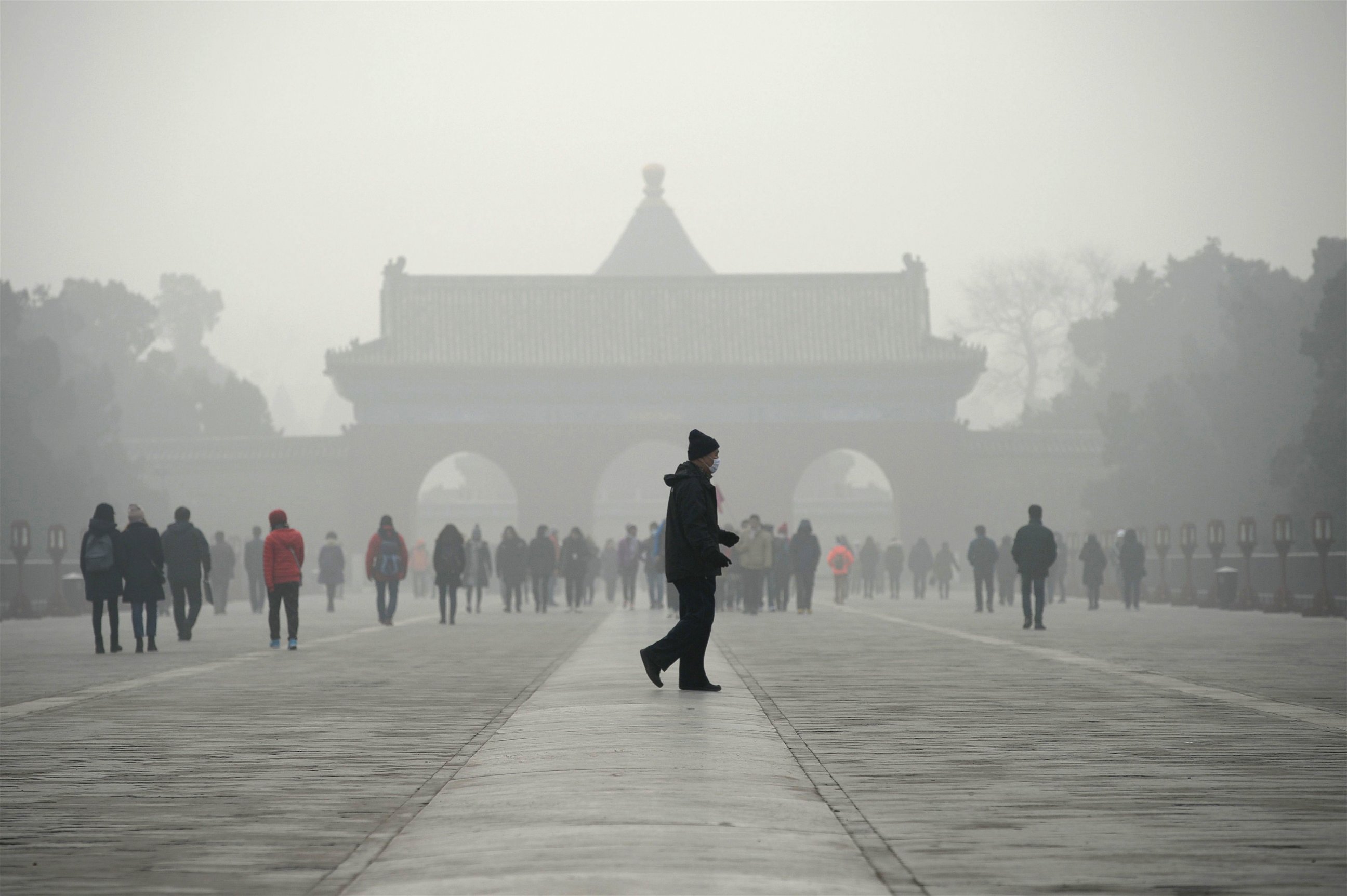 PHOTO: An elderly man walks in front of a group of people during heavy smog at a the Temple of Heaven park in Beijing, Dec. 20, 2016.