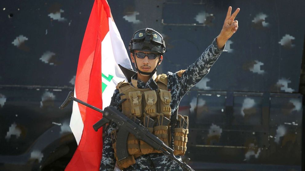An Iraqi federal police member flashes the sign for victory as he celebrates in the Old City of Mosul, July 9, 2017 after the government's announcement of the "liberation" of the embattled city.

