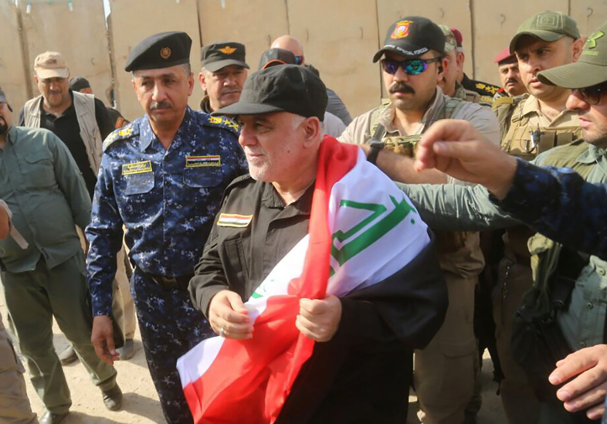 PHOTO: A handout picture released by the Iraqi Federal Police on July 9, 2017, shows Iraqi Prime Minister Haider al-Abadi wrapped in the Iraqi national flag while walking alongside police and army officers upon his arrival in Mosul.