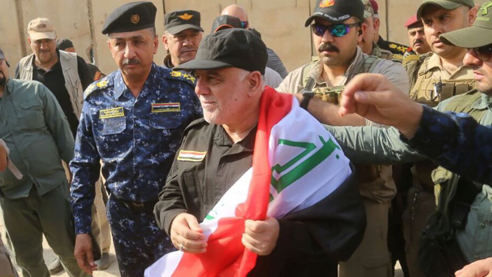 PHOTO: A handout picture released by the Iraqi Federal Police on July 9, 2017, shows Iraqi Prime Minister Haider al-Abadi wrapped in the Iraqi national flag while walking alongside police and army officers upon his arrival in Mosul.
