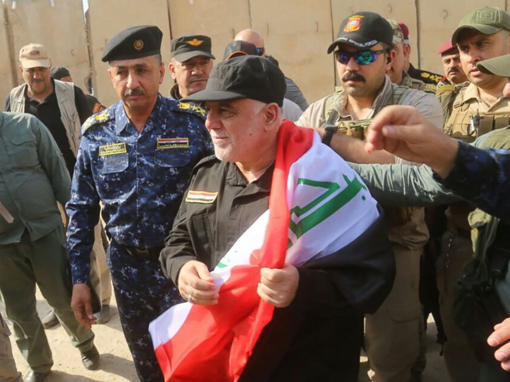 PHOTO: A handout picture released by the Iraqi Federal Police on July 9, 2017, shows Iraqi Prime Minister Haider al-Abadi wrapped in the Iraqi national flag while walking alongside police and army officers upon his arrival in Mosul.