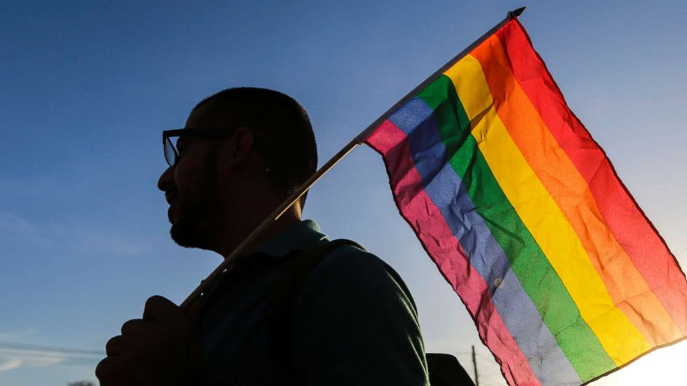 An LGBT community member and supporter holds up a rainbow flag.