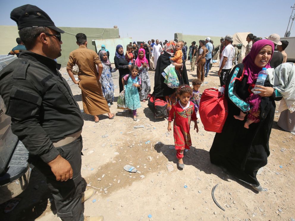 PHOTO: Iraqi security keep watch as civilians arrive on July 27, 2016, at a camp for displaced people in the district of Hajaj after fleeing the towns of al-Shirqat and Qayyarah, south of the city of Mosul.