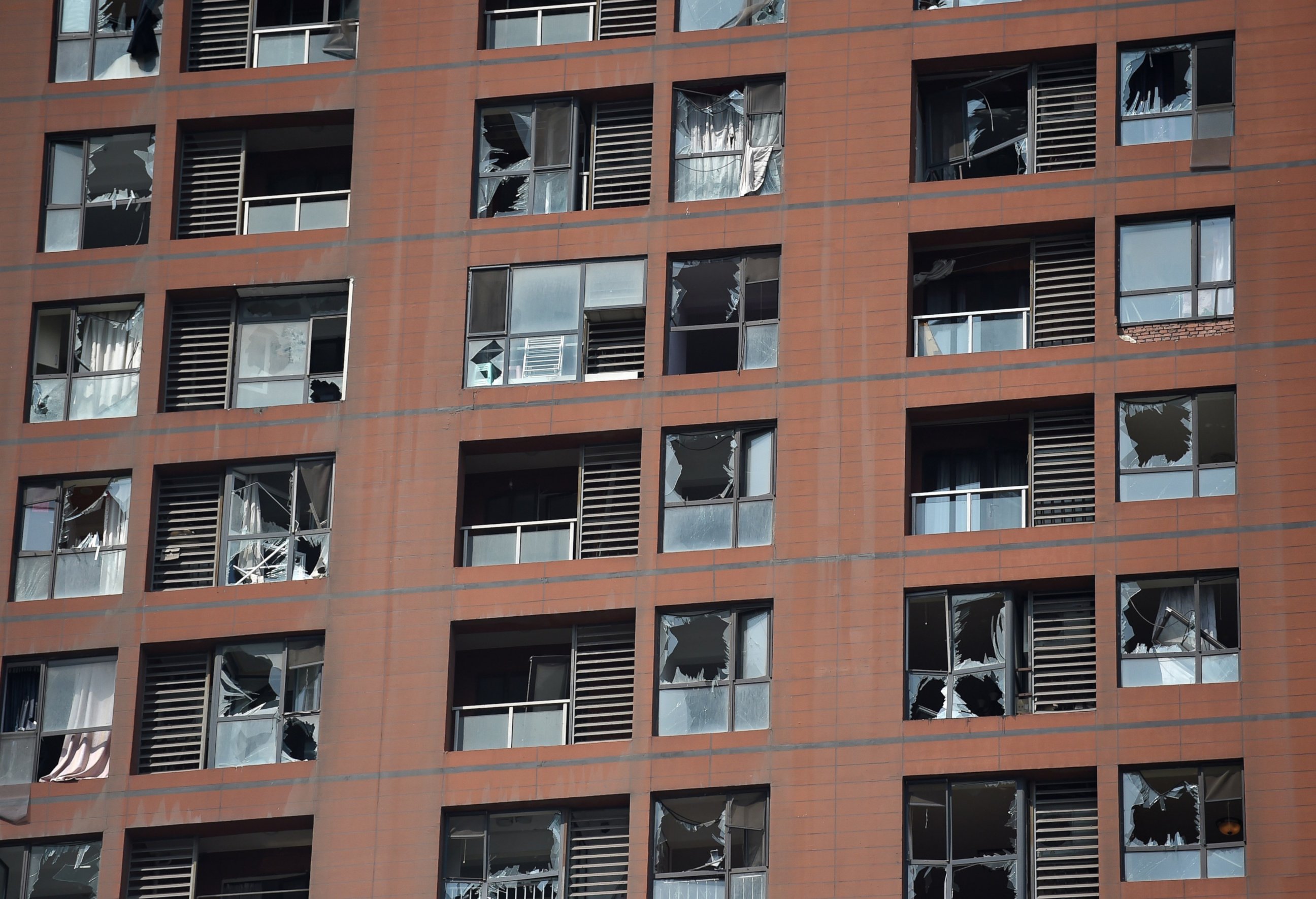 PHOTO: Shattered windows are seen on the facade of a residential building near the site of a series of explosions in Tianjin, China on Aug. 13, 2015. 