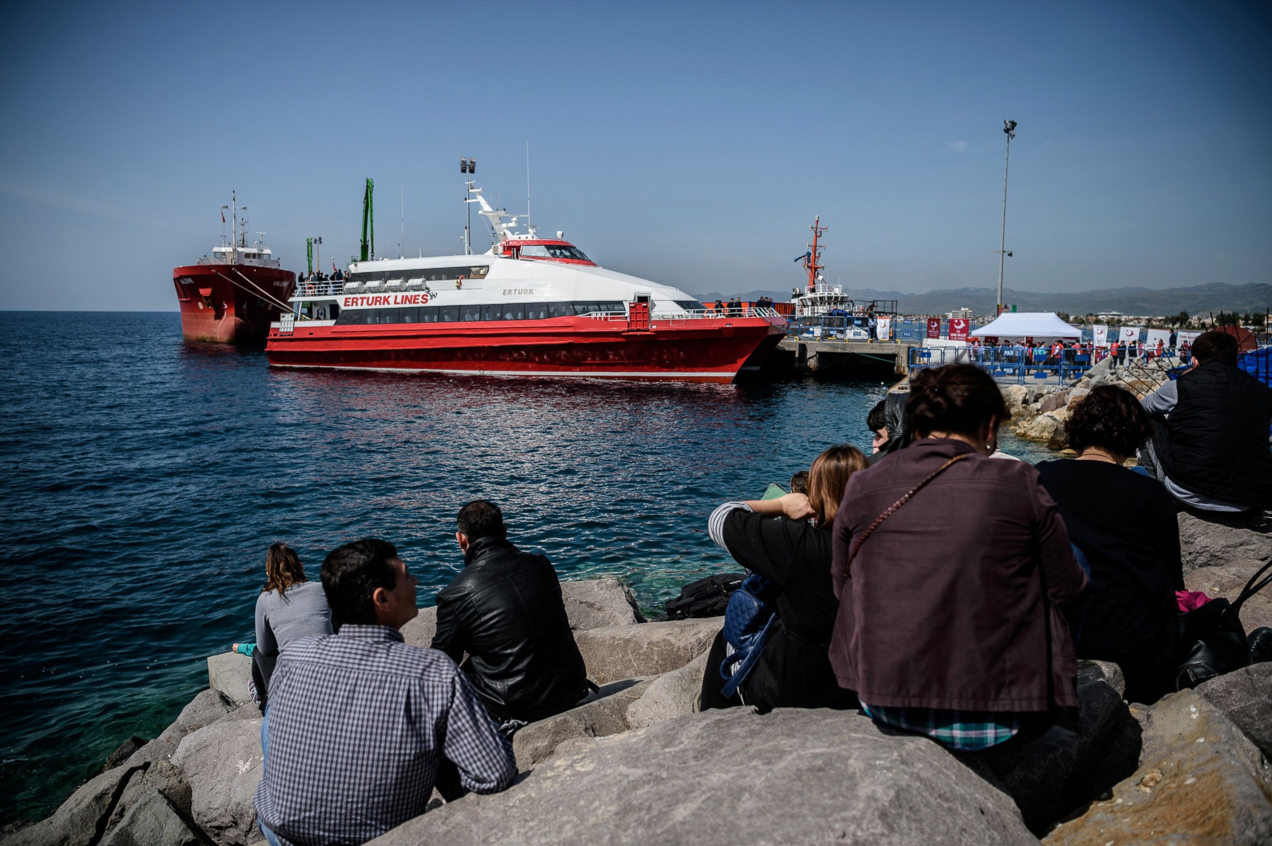 PHOTO: People gather on the beach as migrants deported from Greece arrive aboard a small Turkish ferry in the port of Dikili district in Izmir, Turkey, on April 4, 2016.  