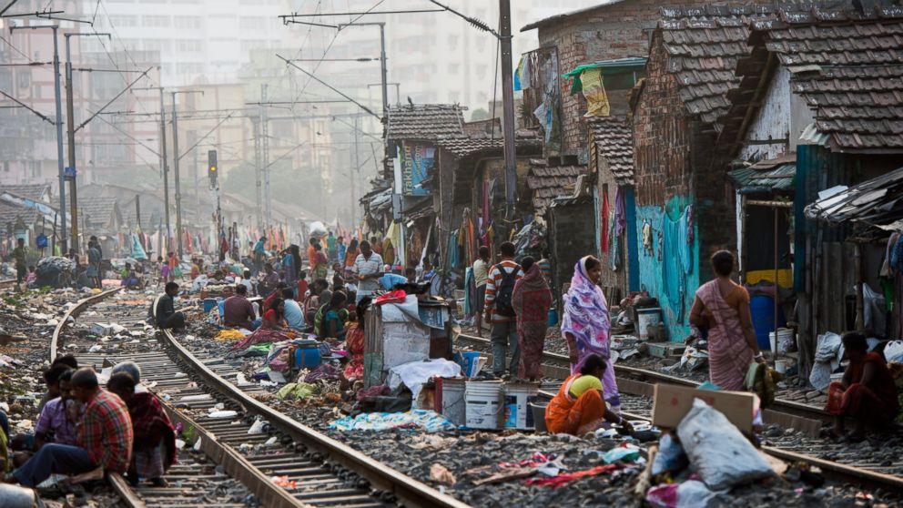 People get on with their lives in a slum on the railway tracks as a commuter train goes past on Dec. 12, 2013 in Kolkata, India. 