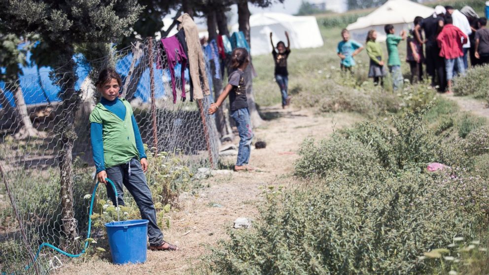 A girl fills a bucket with water at a refugee settlement area with jerry-built tents and hovels in Yuregir district of Adana as they make preparations for the Eid al-Fitr marks the end of the Muslim holy fasting month of Ramadan despite the all harsh conditions at the camp away from their home on July 16, 2015. 