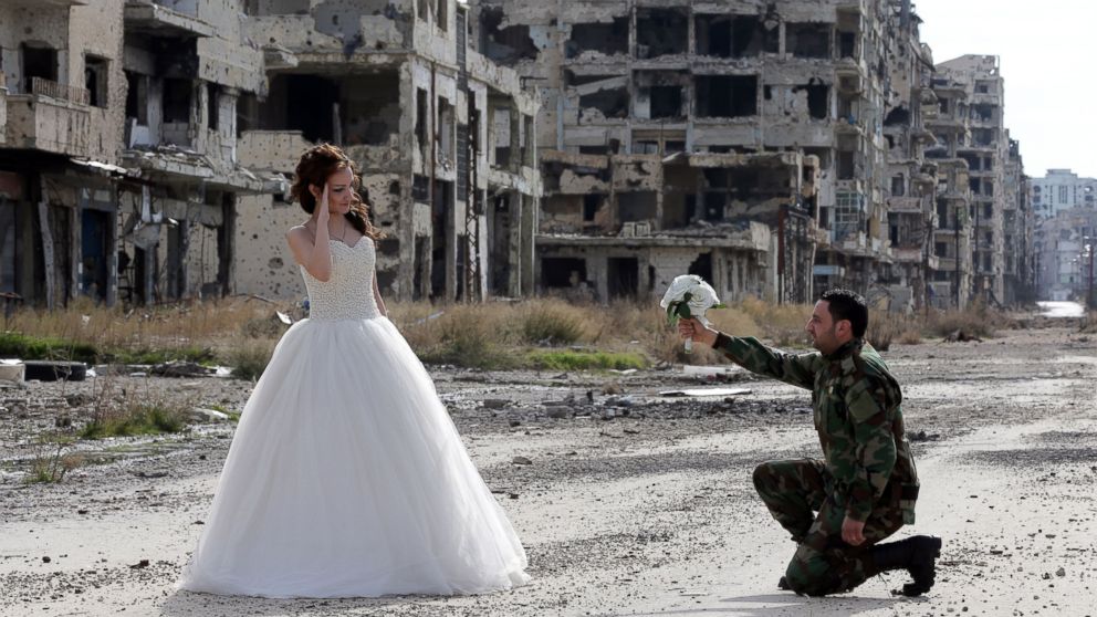 Newly-wed Syrian couple Nada Merhi, and Syrian army soldier Hassan Youssef, pose for a wedding picture amid heavily damaged buildings in the war ravaged city of Homs on February 5, 2016.