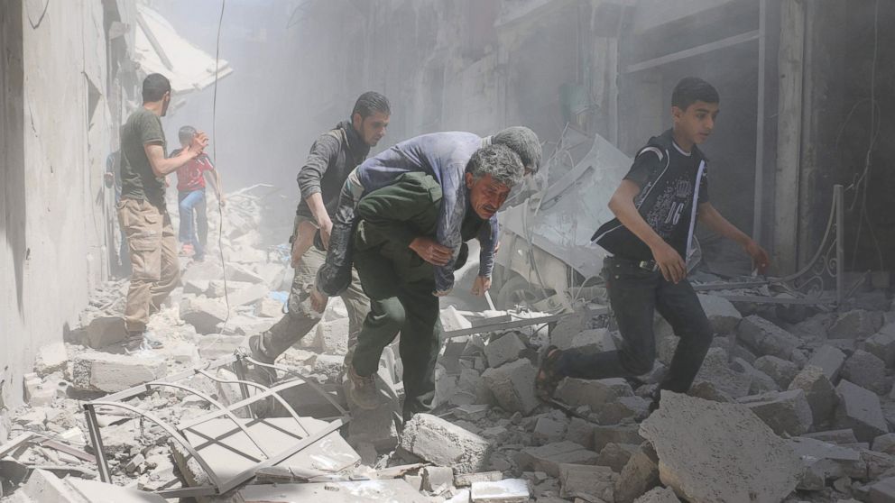 Syrians evacuate an injured man amid the rubble of destroyed buildings following a reported air strike on the rebel-held neighbourhood of Al-Qatarji, in the northern Syrian city of Aleppo, on April 29, 2016. 