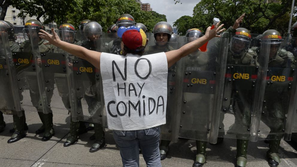PHOTO: A woman with a sign reading "There is no food" protests against new emergency powers decreed this week by President Nicolas Maduro in front of a line of policemen in Caracas, on May 18, 2016. 