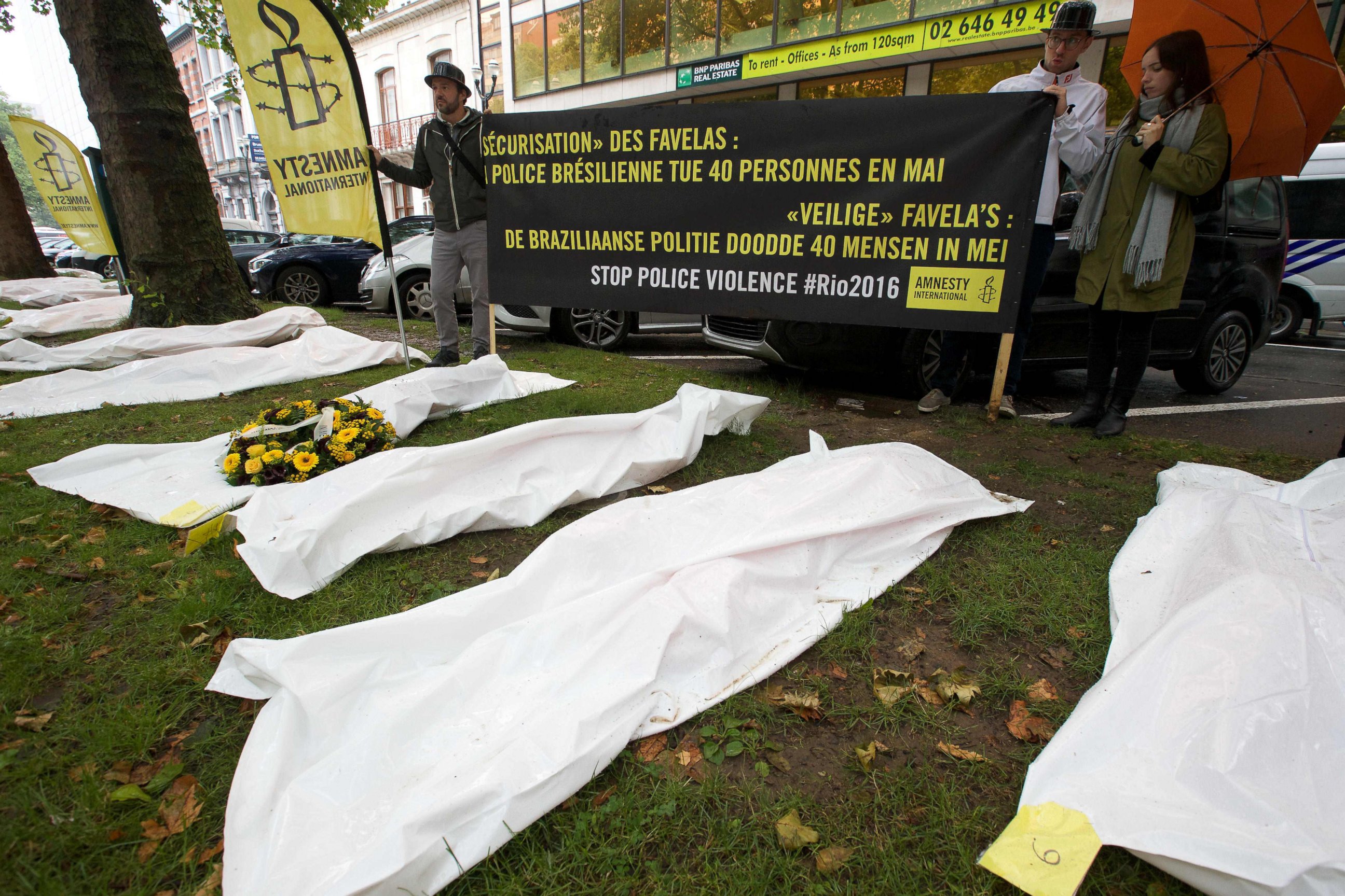 PHOTO: People hold a banner reading "Securing the favelas: The Brazilian police killed 40 people in May" as they stand by white body bags during a demonstration by Amnesty International in Brussels, Aug. 2, 2016.