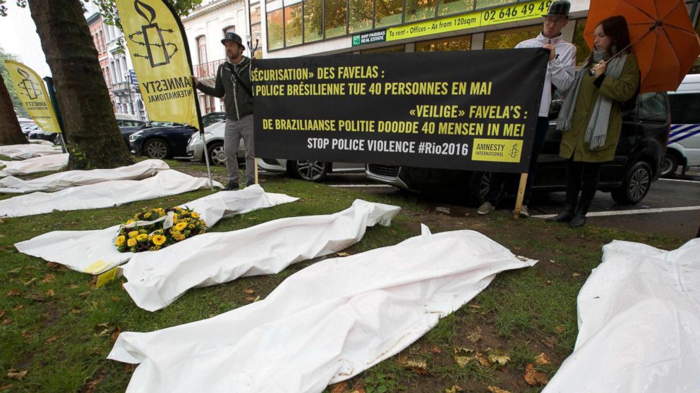 PHOTO: People hold a banner reading "Securing the favelas: The Brazilian police killed 40 people in May" as they stand by white body bags during a demonstration by Amnesty International in Brussels, Aug. 2, 2016.