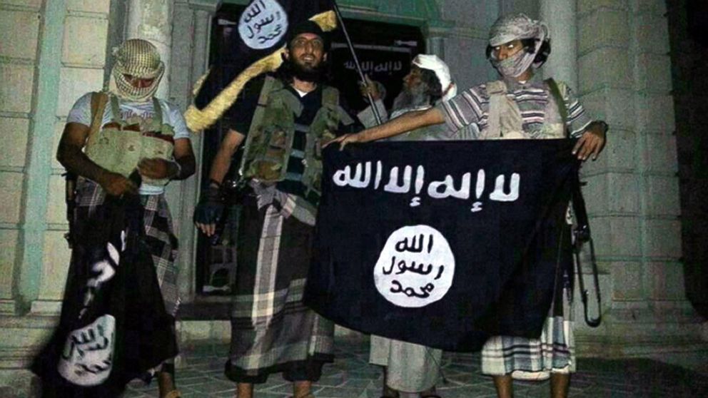 A picture taken with a mobile phone early on May 24, 2014 shows Al-Qaeda militants posing with Al-Qaeda flags in front of a museum in Seiyun, second Yemeni city of Hadramawt province, after launching a massive pre-dawn assault that killed at least 15 soldiers and police. 