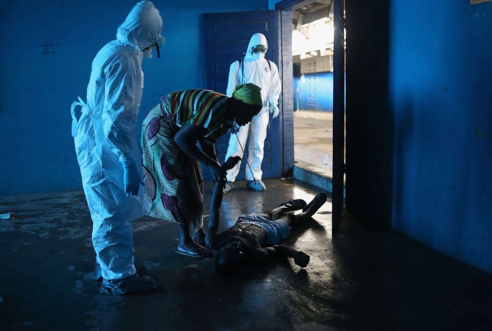 PHOTO: Umu Fambulle tries to help her husband Ibrahim after he fell and was knocked unconscious in an Ebola ward on Aug. 15, 2014, in Monrovia, Liberia.