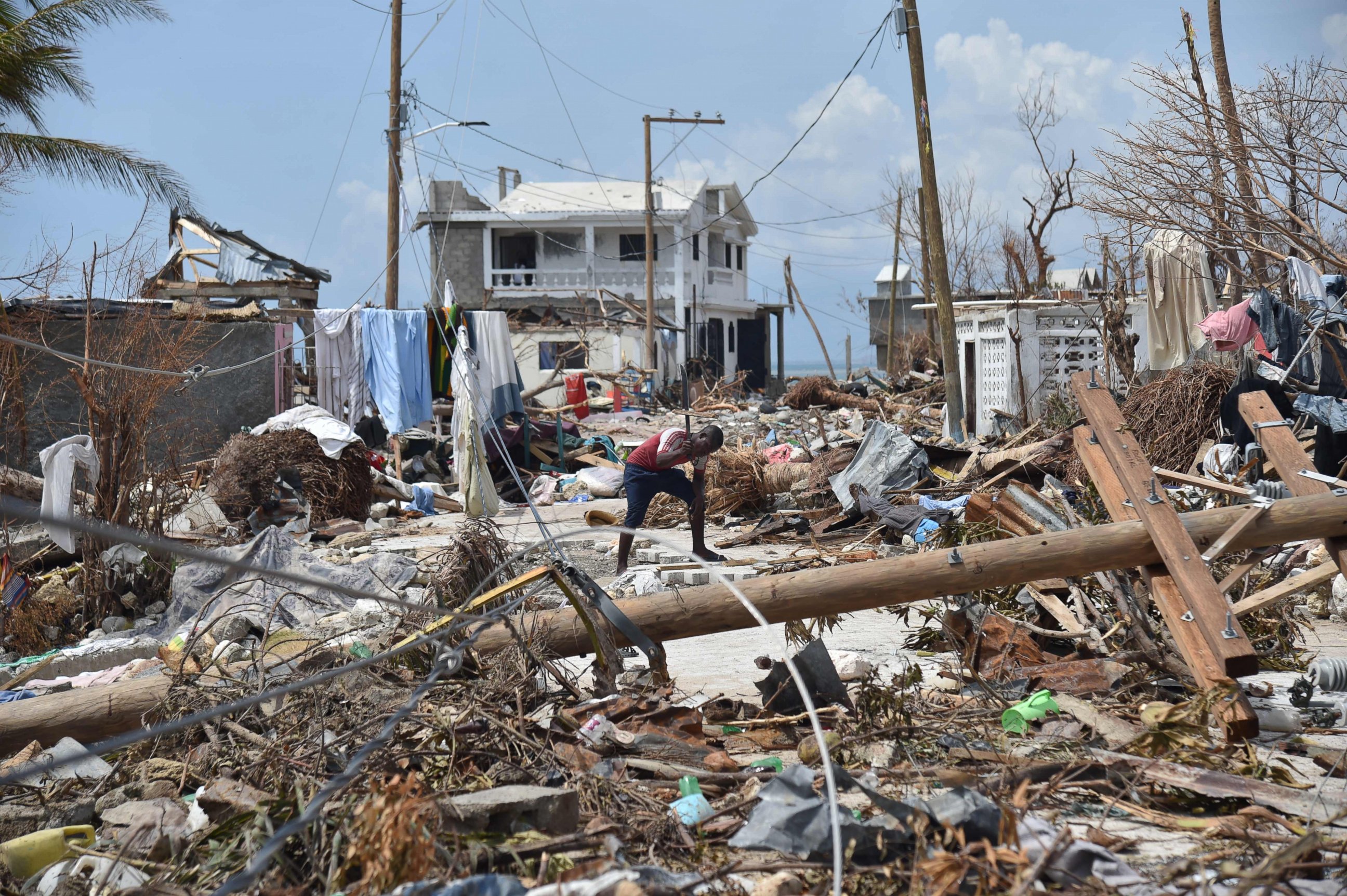 PHOTO: A young man cuts a piece of wood in a street of Les Cayes, Haiti, Oct. 10, 2016, following the passage of Hurricane Matthew.