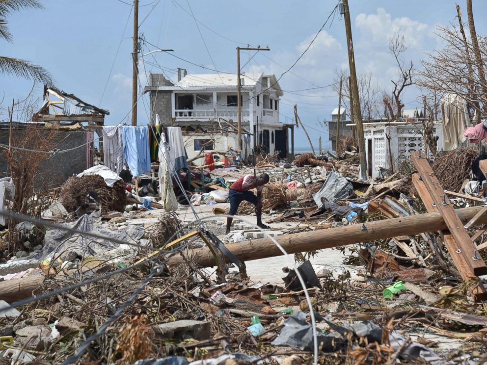 PHOTO: A young man cuts a piece of wood in a street of Les Cayes, Haiti, Oct. 10, 2016, following the passage of Hurricane Matthew.