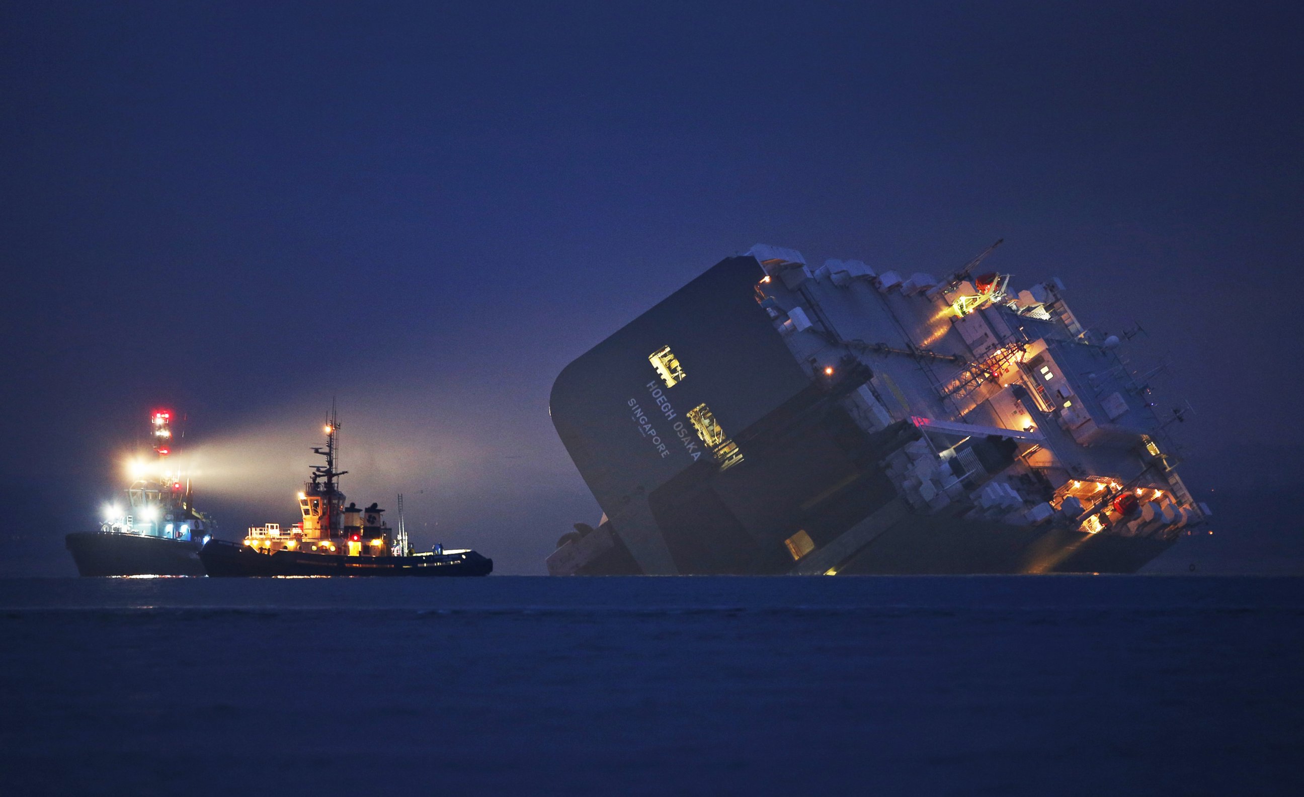 PHOTO:  A salvage tug lights the hull of the Hoegh Osaka cargo ship after it ran aground