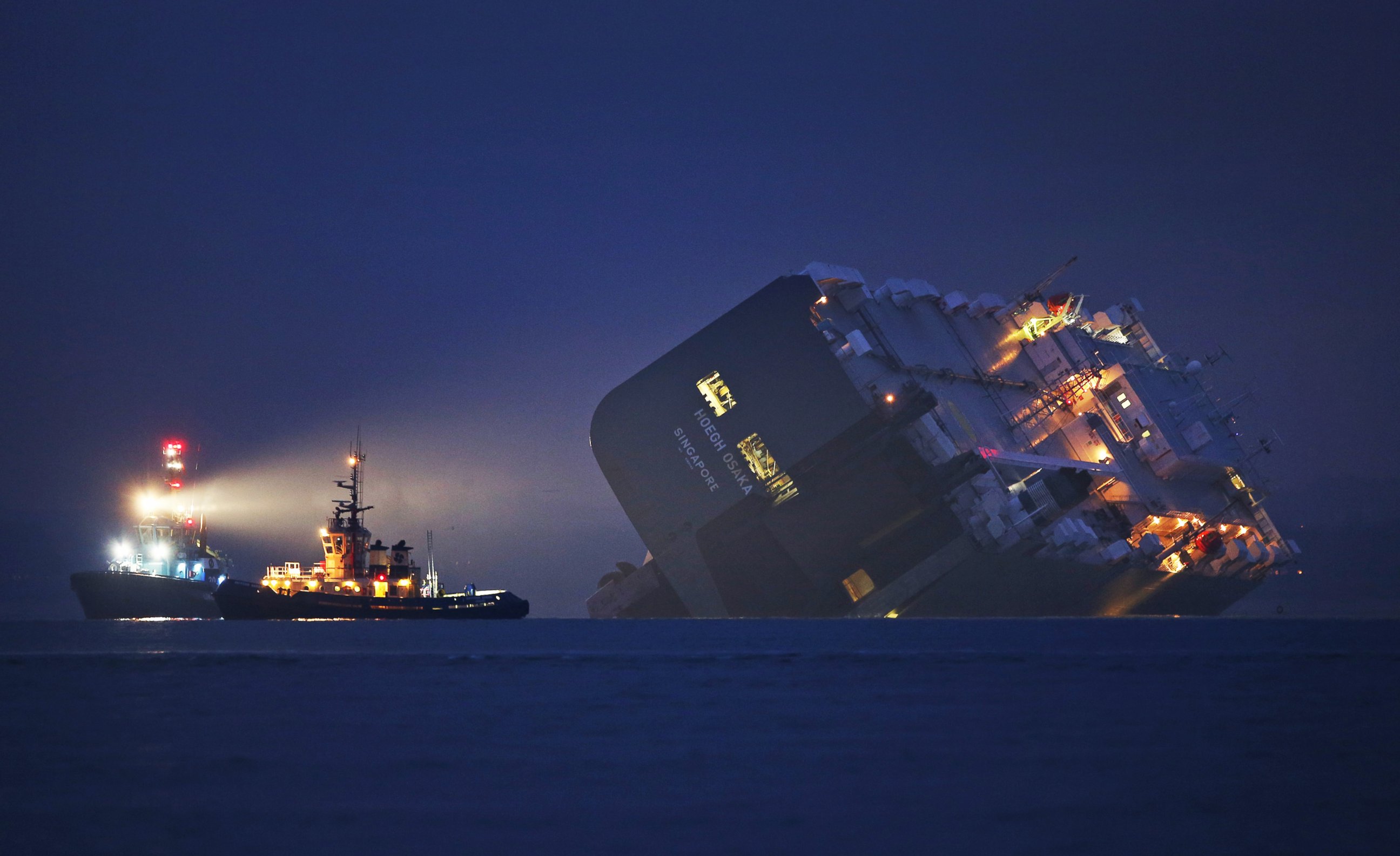 PHOTO: A salvage tug lights the hull of the Hoegh Osaka cargo ship after it ran aground