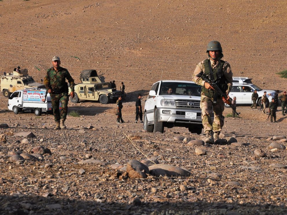 PHOTO: Members of the Kurdish Peshmerga forces take a position to fight